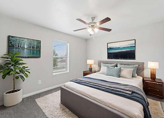 A bedroom with a large bed and a ceiling fan.