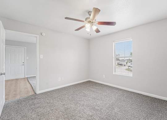 A room with a ceiling fan and a window with blinds.