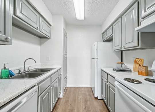 A kitchen with white appliances and grey cabinets.