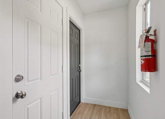 A white door with a silver handle is next to a red fire extinguisher.