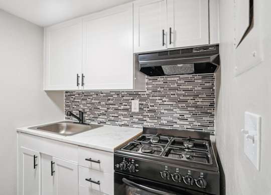 A kitchen with a black stove top oven and white cabinets.