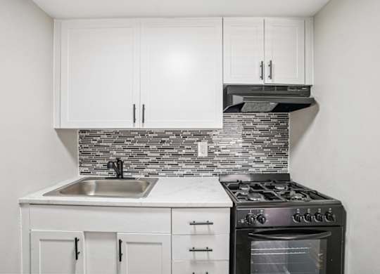 A kitchen with white cabinets and a black stove top oven.