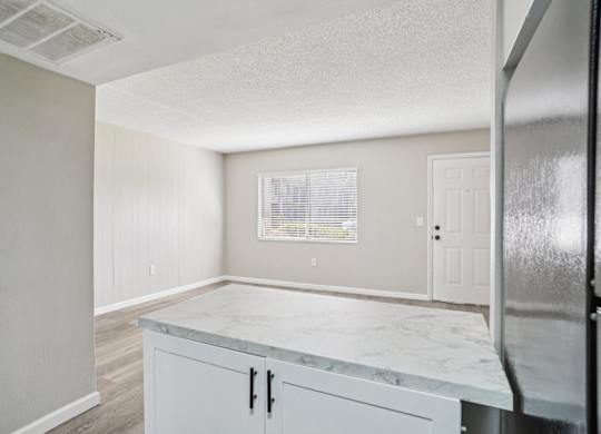 A kitchen with a marble countertop and white cabinets.