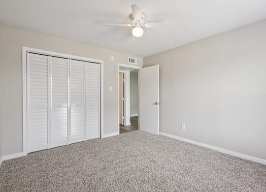 A room with a ceiling fan and carpeted floor.