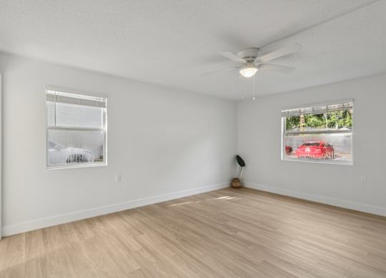 A room with a ceiling fan and two pictures on the wall.