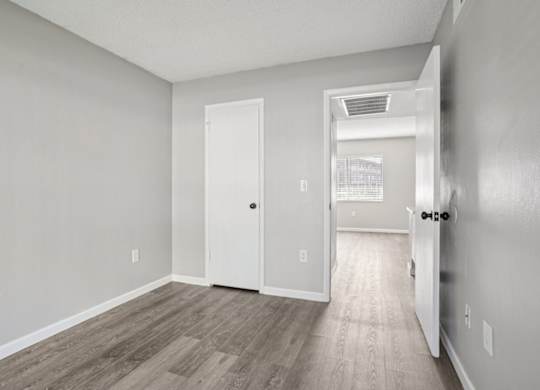 A room with a white door and a wooden floor.