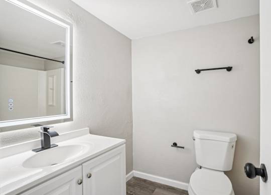 A white bathroom with a toilet, sink, and mirror.