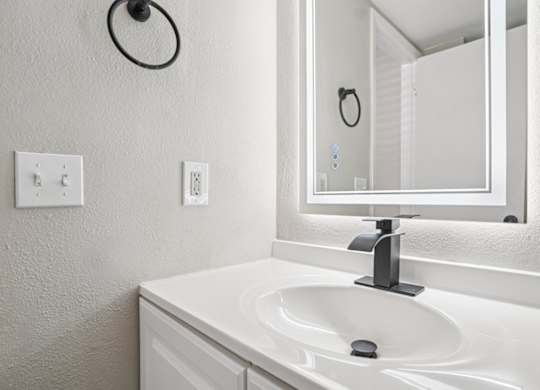 A white sink in a bathroom with a mirror above it.