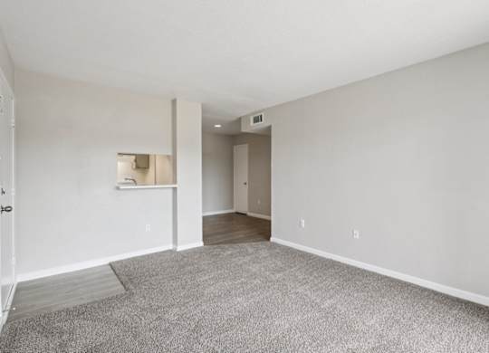 A spacious room with a carpeted floor and white walls.