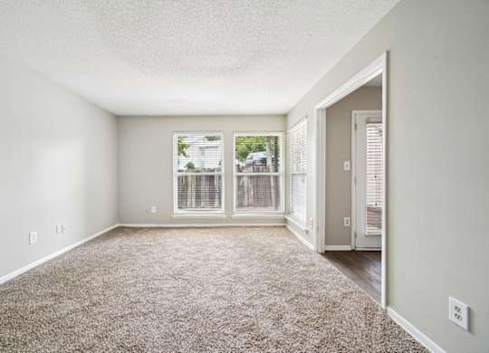 A room with a carpeted floor and a window with blinds.