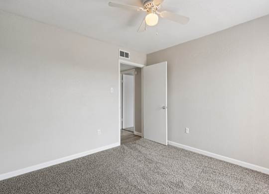 A room with a ceiling fan and carpeted floor.