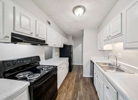 A kitchen with white cabinets and a black stove top oven.