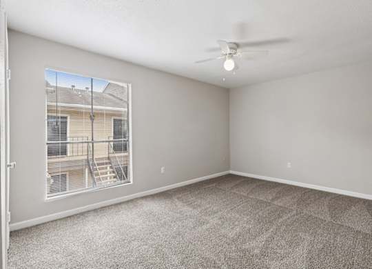 A room with a carpeted floor and a ceiling fan.