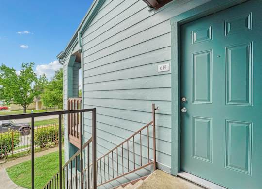 A blue door is on the right side of a house with a white siding.