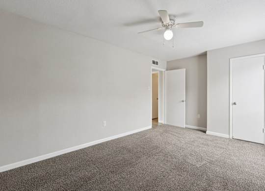 A room with a ceiling fan and carpeted floor.