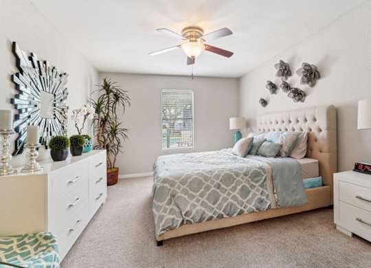A bedroom with a bed, nightstands, and a ceiling fan.