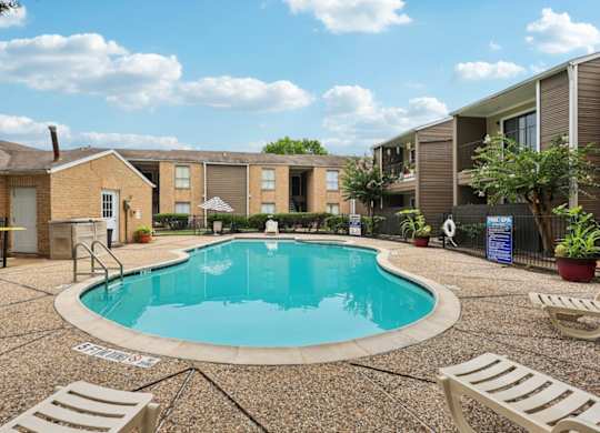 A small pool surrounded by a concrete patio and lounge chairs.