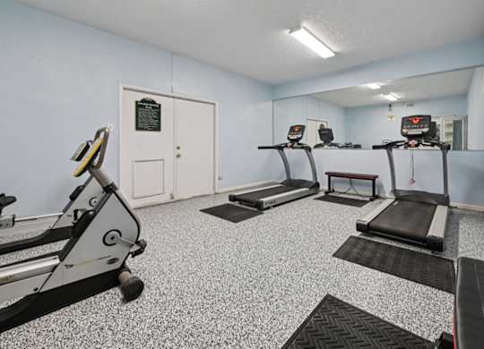 A gym with treadmills and a mirror.