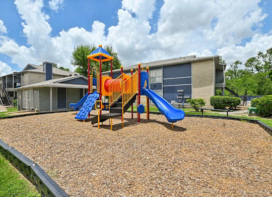 A playground with a blue and orange slide in the foreground.