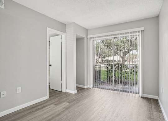 A room with a sliding glass door leading to a backyard.