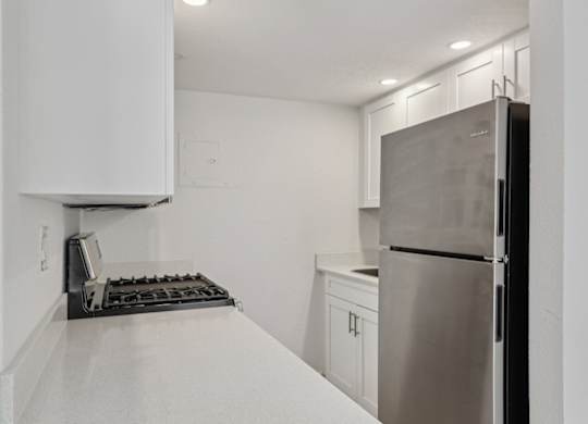 A kitchen with a stainless steel refrigerator and a white countertop.
