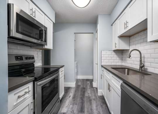 a large kitchen with white cabinets and black appliances at Ascot Place Apartments, Birmingham, 35235