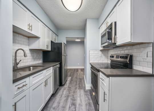 a modern kitchen with white cabinets and stainless steel appliances at Ascot Place Apartments, Birmingham, AL