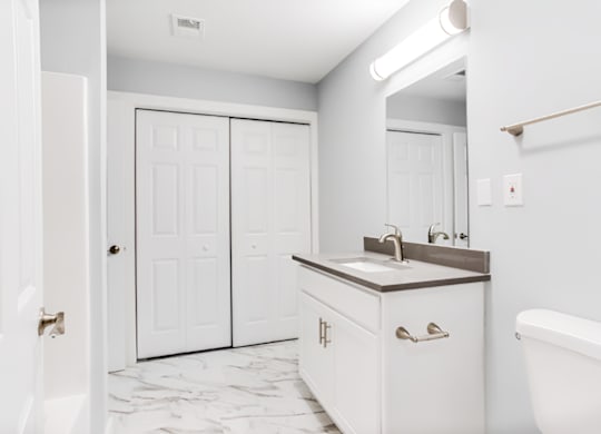 a bathroom with white cabinets and a sink and a mirror at Ascot Place Apartments, Birmingham, 35235