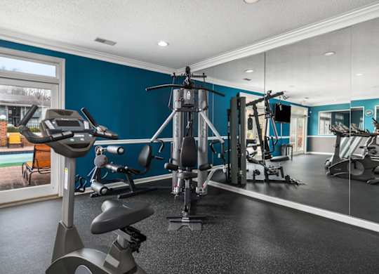 a gym with weights and cardio equipment in a home with blue walls and a window at Ascot Place Apartments, Birmingham Alabama