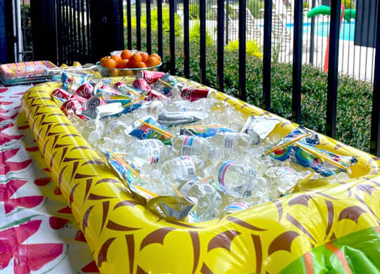 A table covered with a yellow tablecloth and filled with plastic bottles.