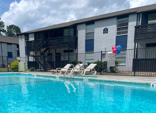 A pool with chairs and a balloon in front of a building.