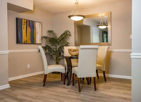 a dining room with a table and chairs and a potted plant at Crestwood Green Apartments, Birmingham, AL 35212