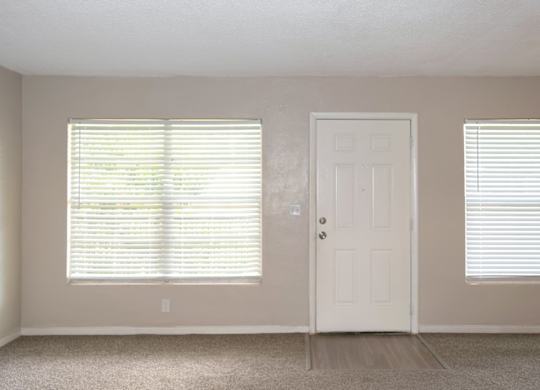 a spacious living room with large windows, a door