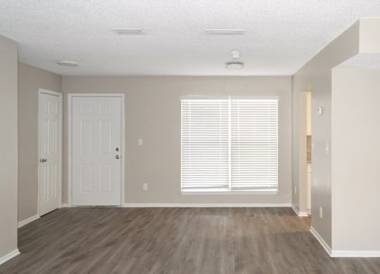 an empty living room with a large window and wooden floors