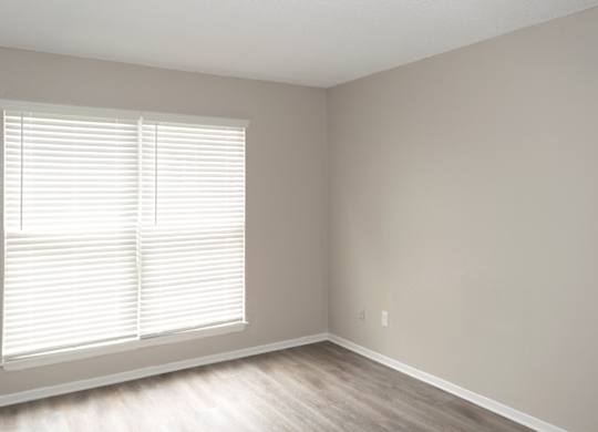 a bedroom with large windows, wood-style flooring, and neutral paint colors