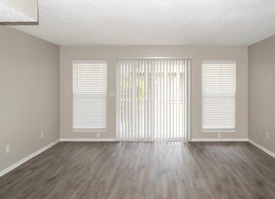 an spacious living room with white blinds and wood flooring