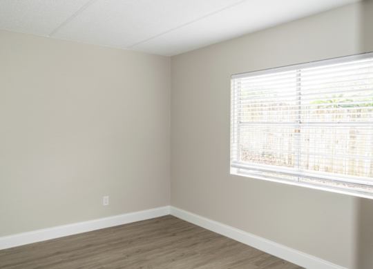 a spacious bedroom with a large window and wood-style floor at Ridge Apartments