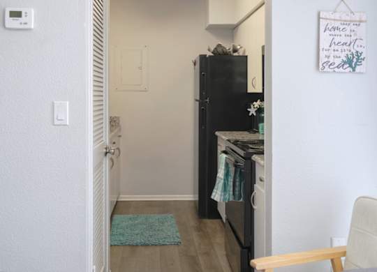 a galley kitchen with black appliances and wood-style flooring