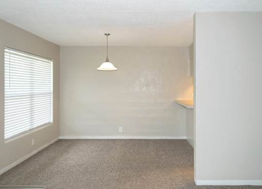 A dining room with a carpeted floor and a hanging light fixture.