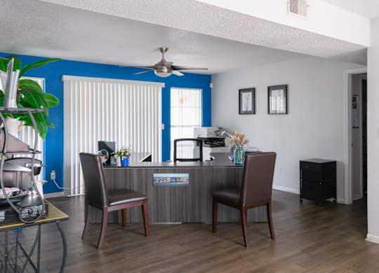a kitchen and living room with a desk and chairs