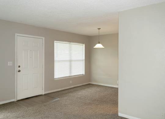 a living and dining area with overhead lighting and natural light from windows