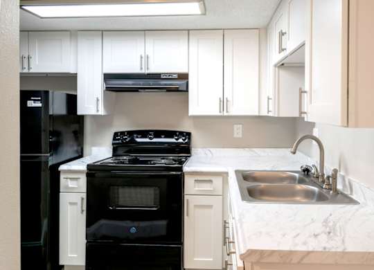 a fully equipped kitchen with black appliances and white cabinets at Ridge Apartments