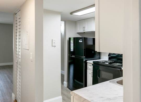 a kitchen with black appliances and white cabinets in a Ridge Apartment home