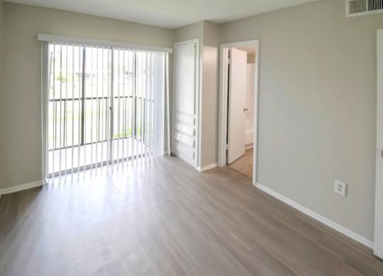 A bedroom with wood-style floors and sliding glass doors to a private balcony