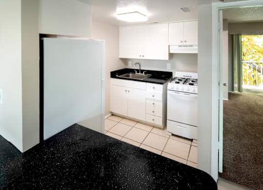 a kitchen with white appliances and black counter tops