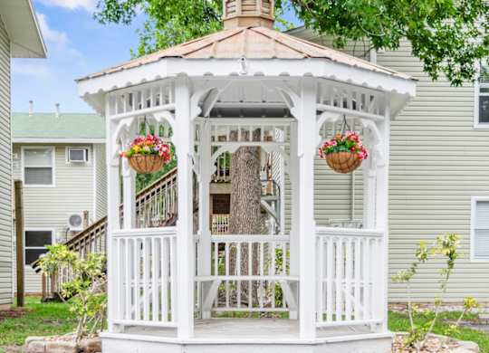 a white gazebo with two hanging pots of flowers in the Haven on Canal courtyard