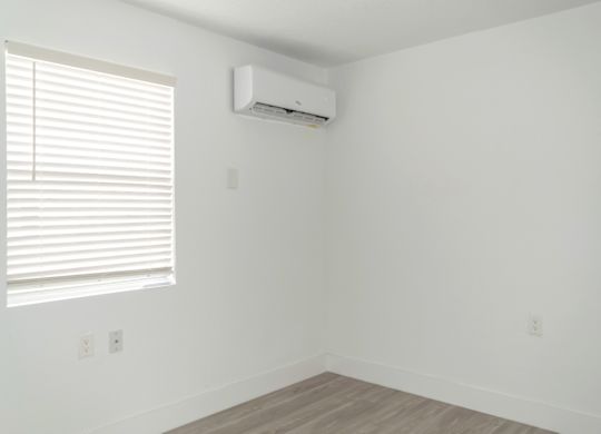 a bedroom with a mini-split on the wall and a large window