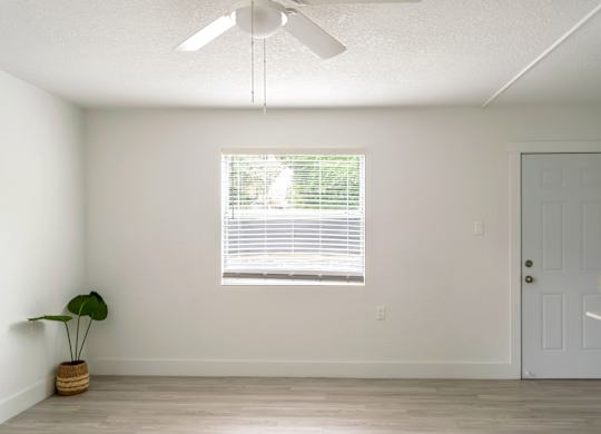 an spacious living room with a window and an illuminated ceiling fan