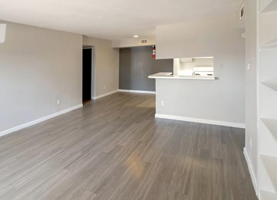a spacious living room with built-in shelves and wood-style floors
