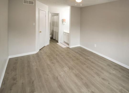 a spacious bedroom with wood-inspired flooring at Pine Creek Apartments